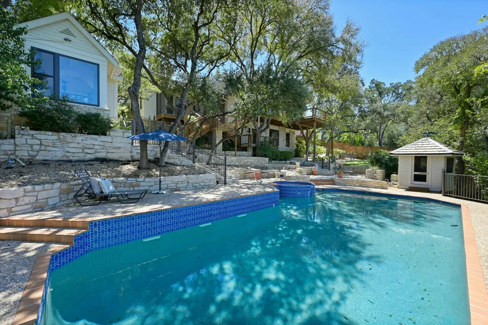 Pool with blue tile and a small pool house