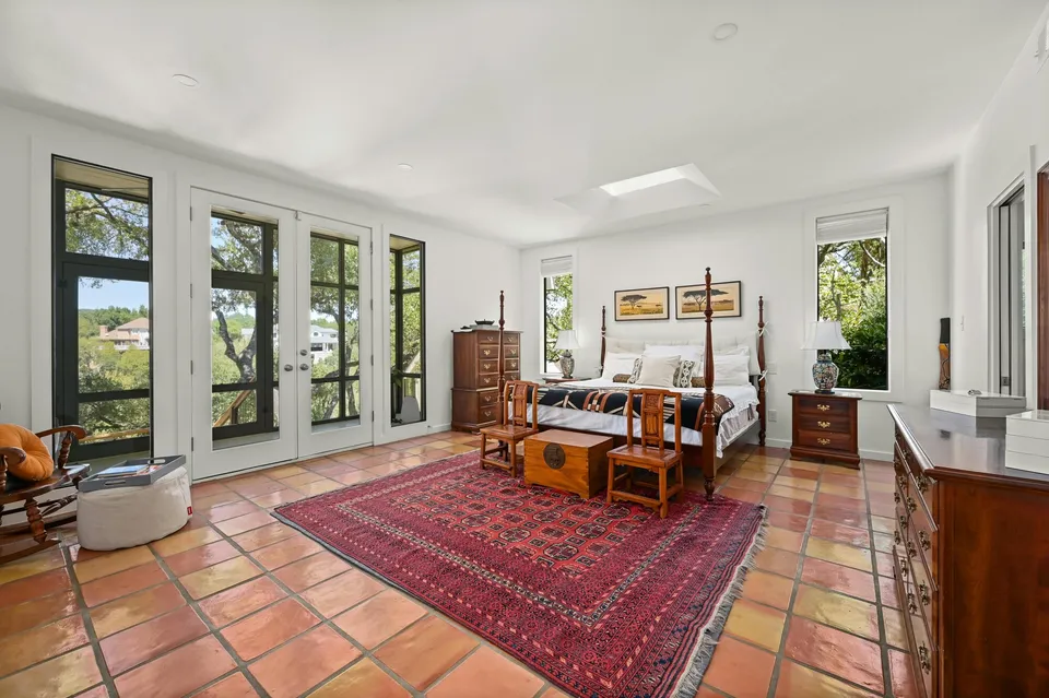 Primary bedroom with Saltillo tile, a red rug and French doors to the patio