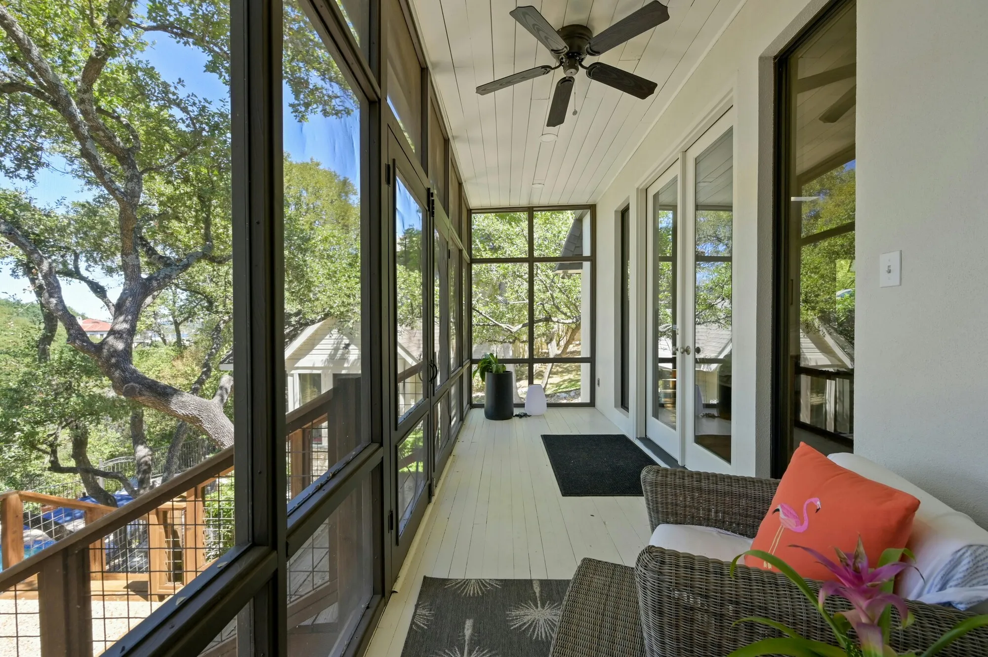 Screened porch with a wicker sofa among oak trees