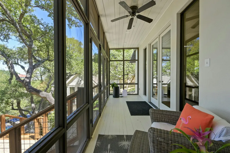 Screened porch with a wicker sofa among oak trees