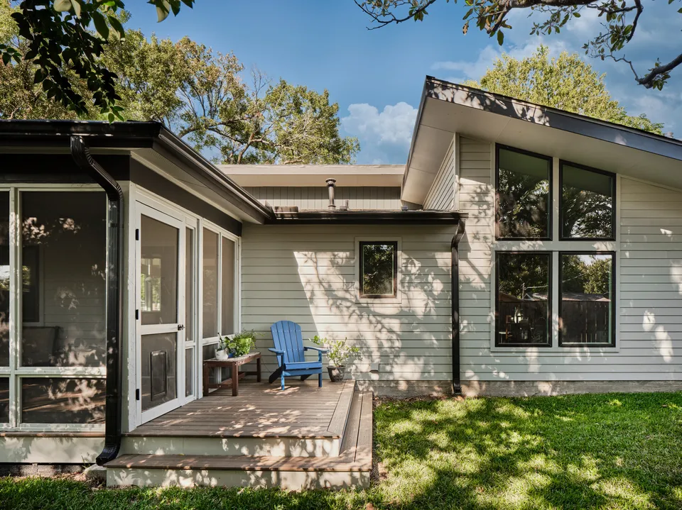 Back of a house with a screened porch and deck beside a wing with tall windows