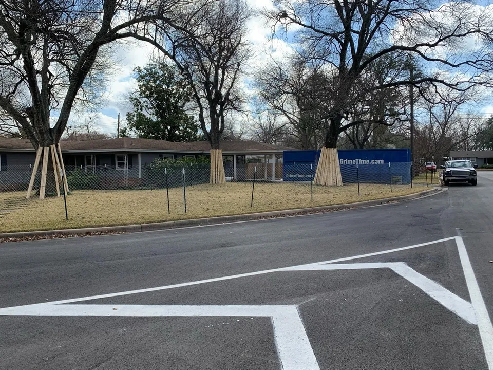 Street corner and the house before the remodel, behind a construction fence