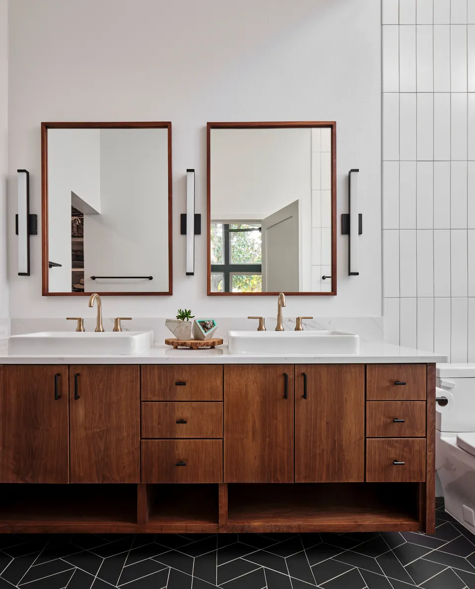 Walnut double vanity with brass faucets and two wood-framed mirrors