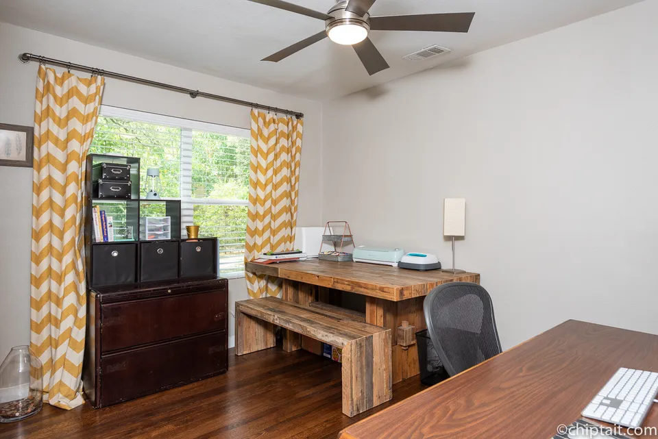 Bedroom used as an office with a wood desk and yellow chevron curtains