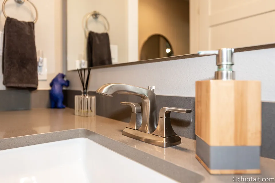 Close view of a brushed nickel faucet on a grey quartz counter