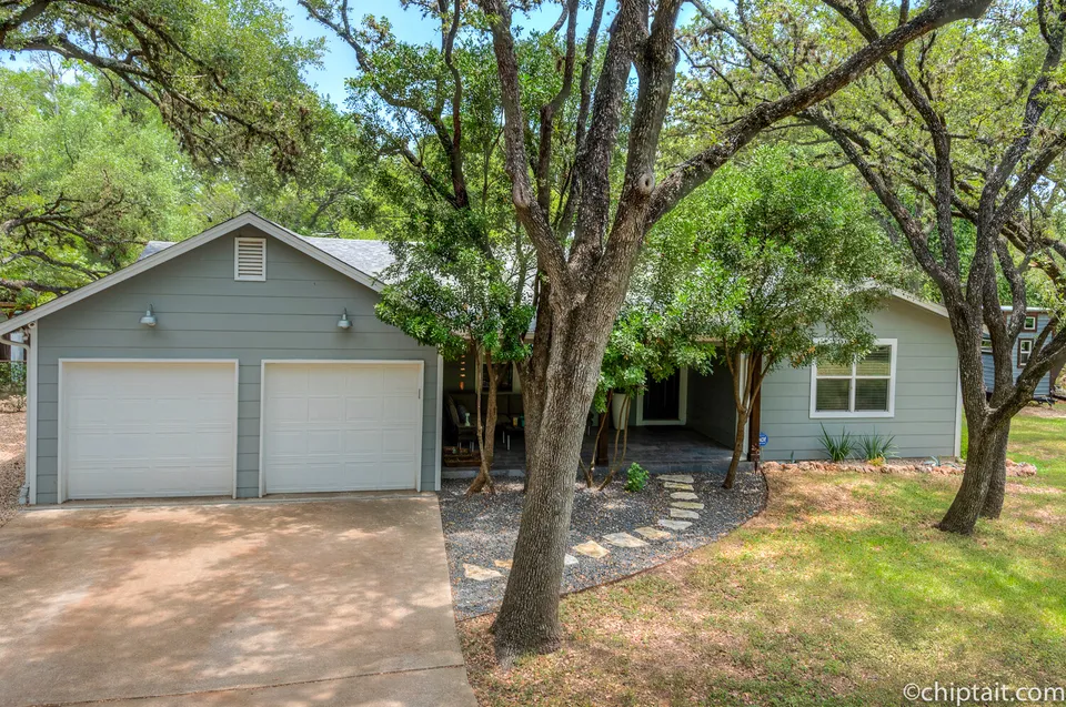 Detached two-car garage and the front of the house among oak trees