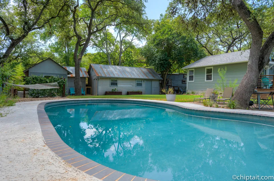 Kidney-shaped pool with brick coping and the house beyond