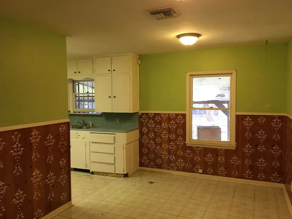 Kitchen before the renovation, with green walls, dated cabinets and patterned wainscoting