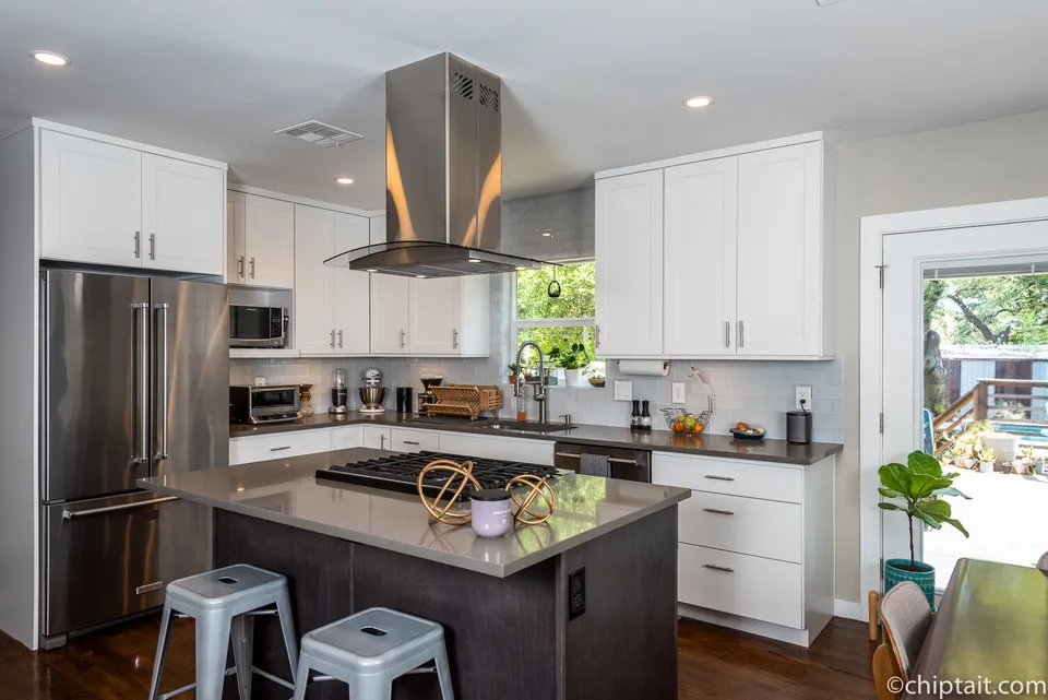 Kitchen with a stainless refrigerator, a dark island and metal bar stools
