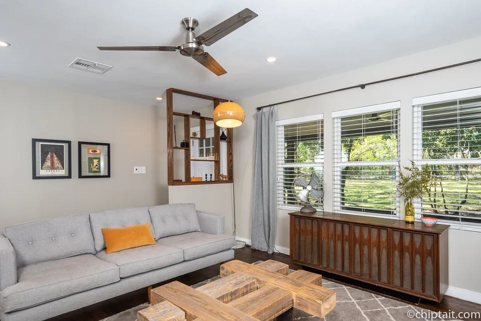 Living room with a grey sofa, a walnut credenza and large windows