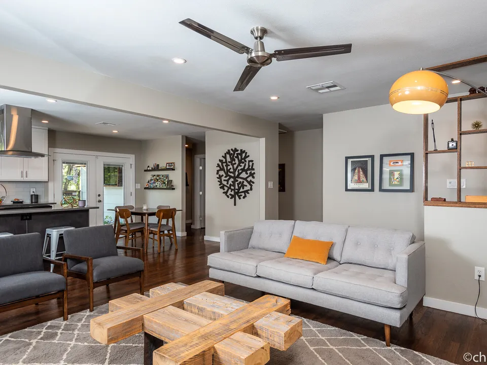 Open living room after the renovation, with a grey sofa and the kitchen beyond