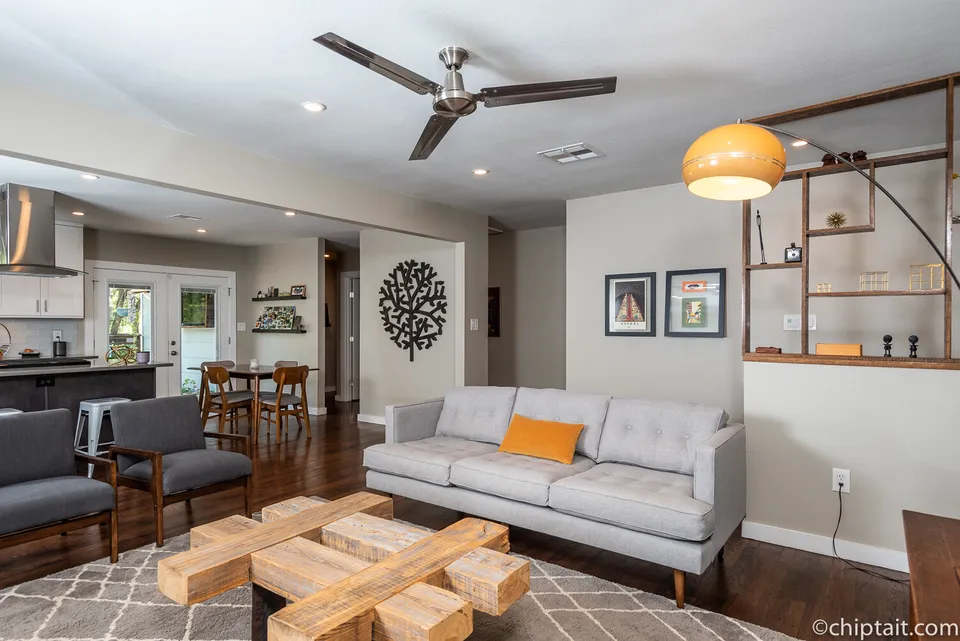 Open living room with a grey sofa, a wood block coffee table and the kitchen beyond