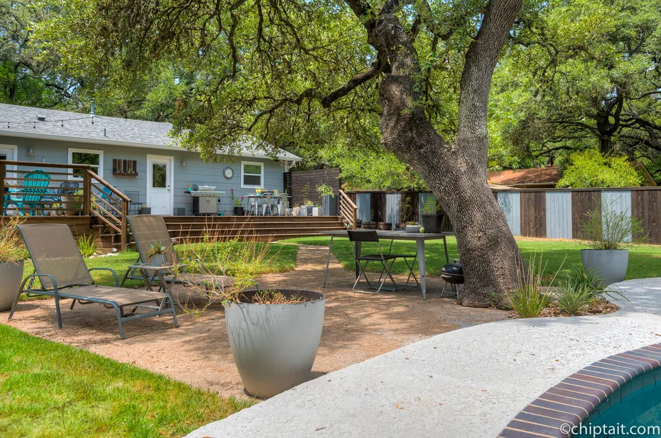 Pool deck with lounge chairs and a planter below the back of the house