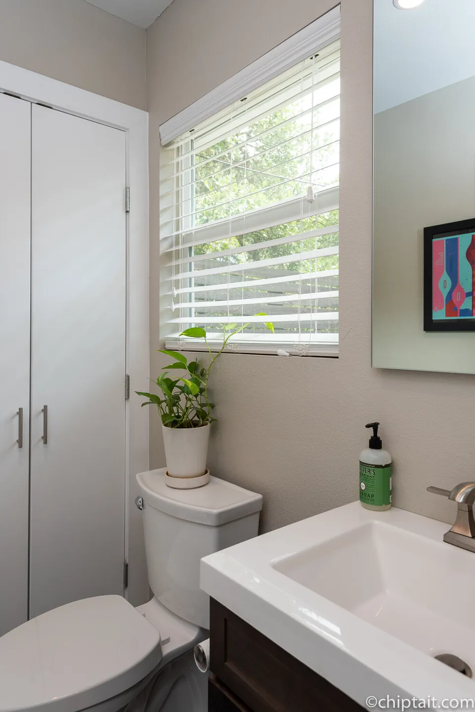 Powder room with a white vanity, a window and a closet door