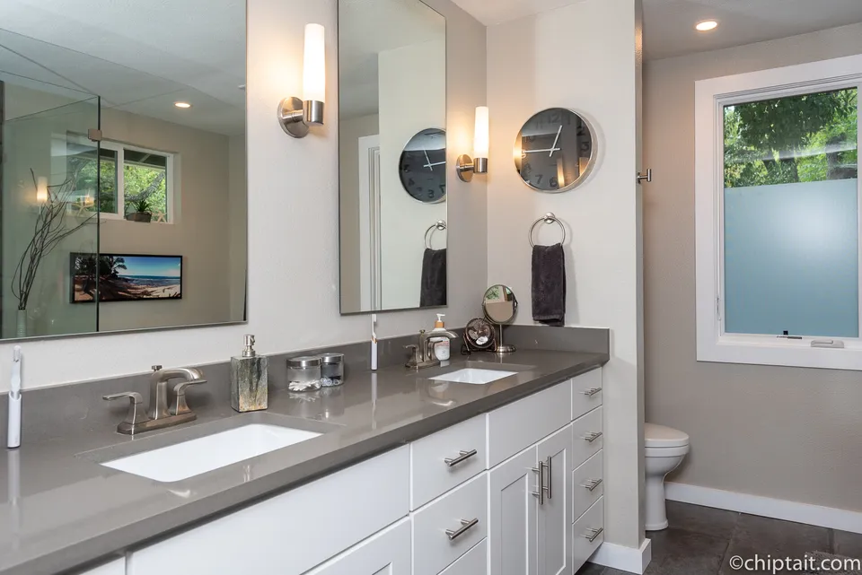 Primary bath with a grey quartz double vanity and a frosted window