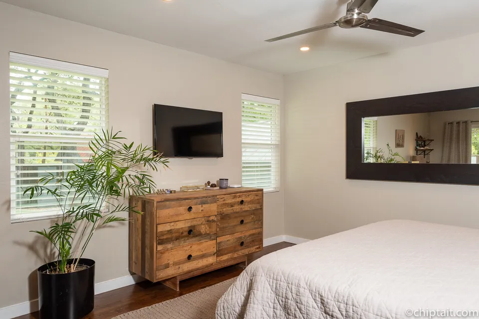 Primary bedroom with a reclaimed wood dresser and a wall-mounted TV