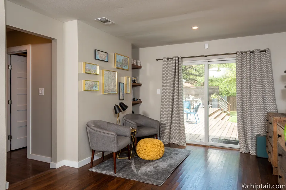 Primary bedroom sitting area with a yellow pouf and sliding doors to the deck