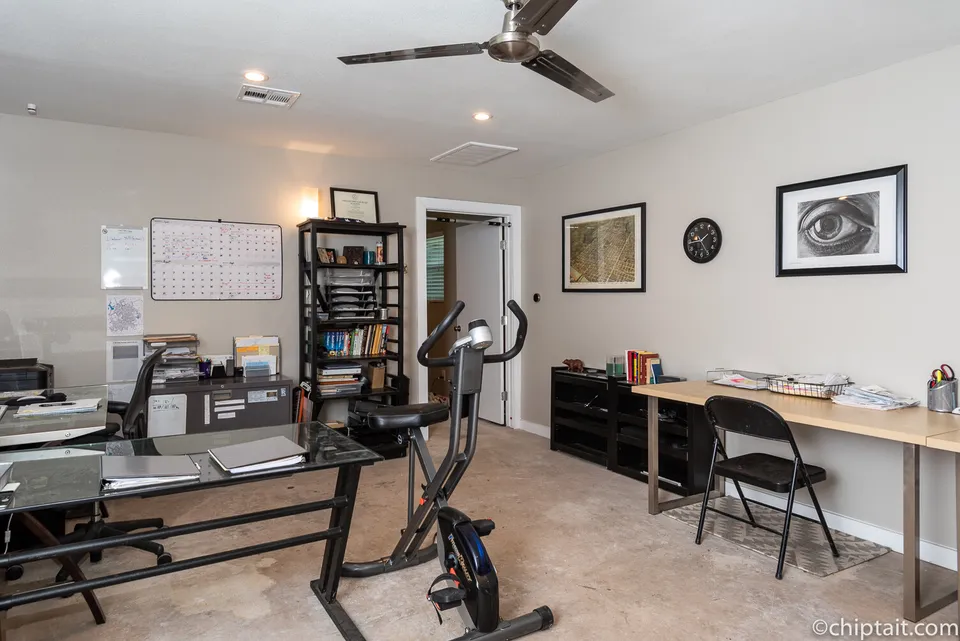 Studio office with a desk, an exercise bike and framed prints
