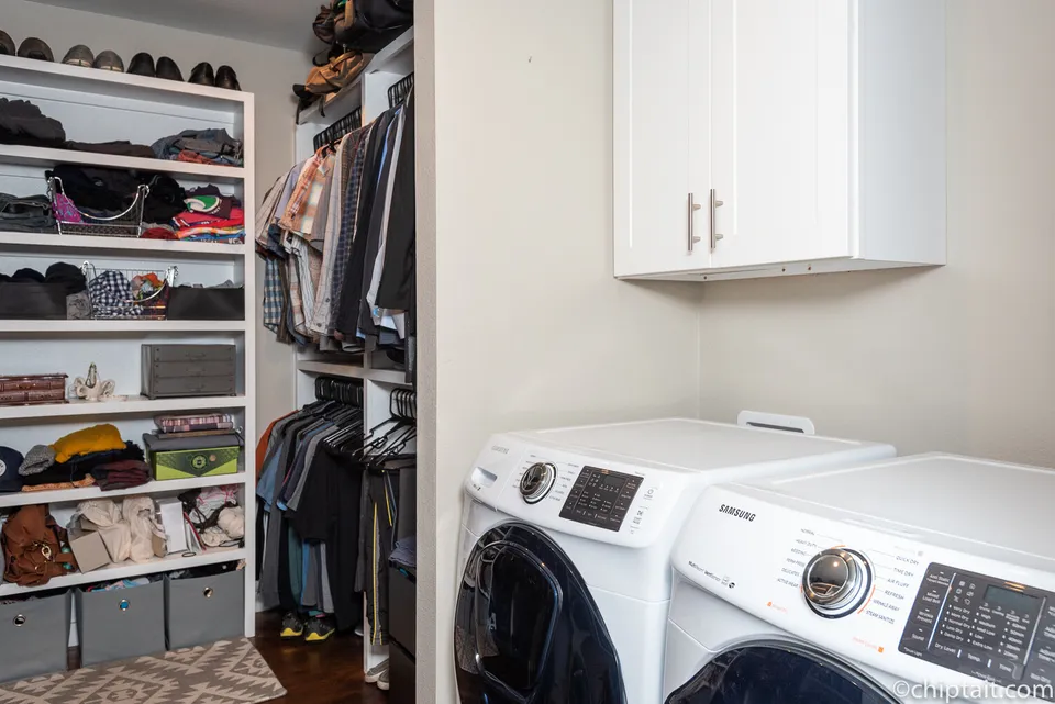 Walk-in closet with open shelving beside a white washer and dryer