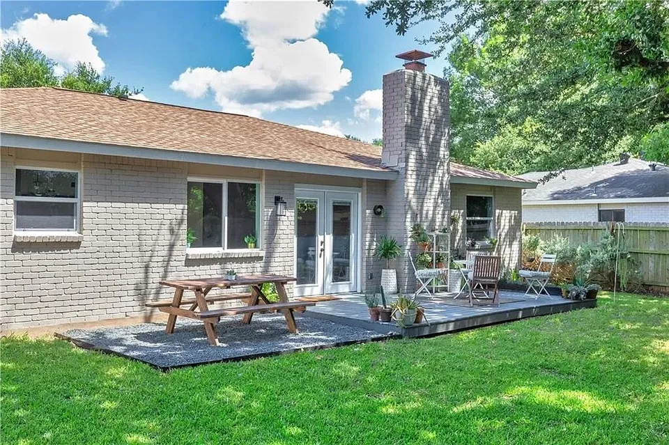 Back deck with a picnic table and French doors on a painted brick house