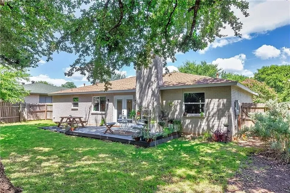 Backyard with a large tree, a deck and patio furniture