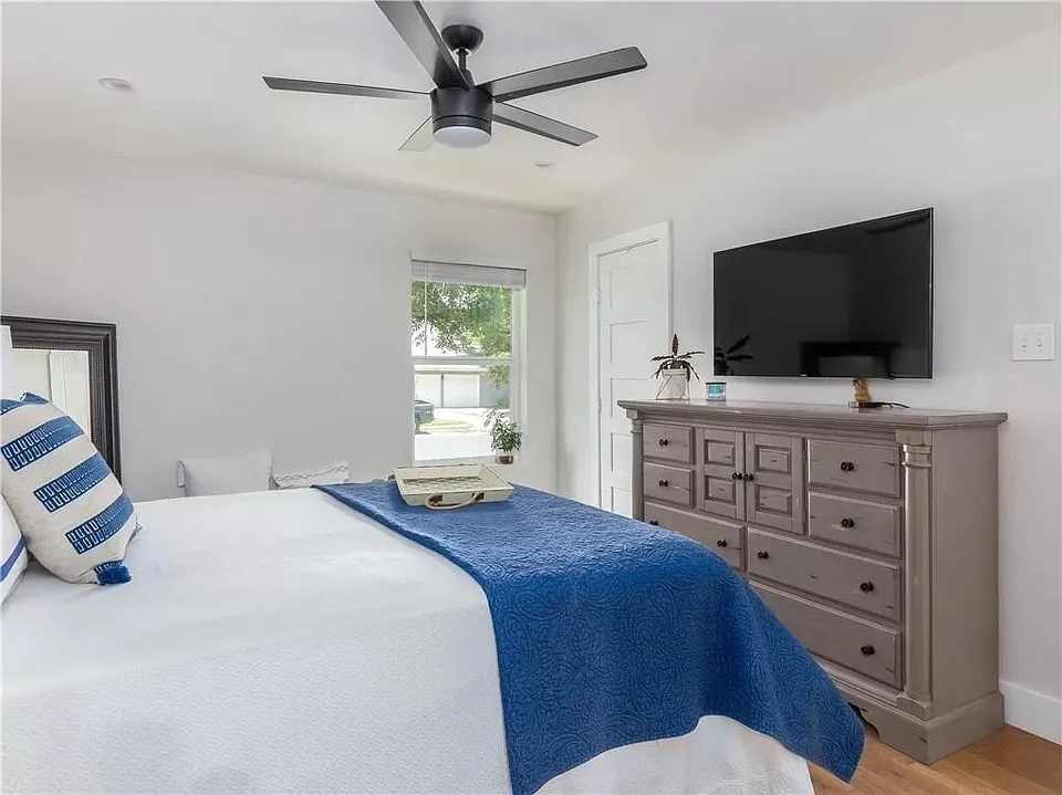 Bedroom with a grey dresser, a TV and a navy bedspread