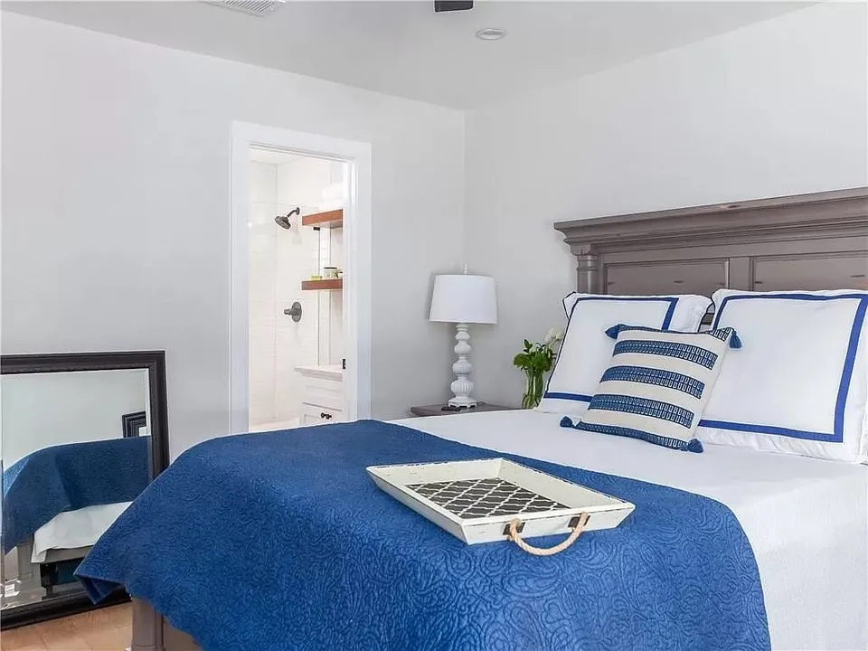 Bedroom with a wood headboard, navy bedding and a doorway to the bathroom