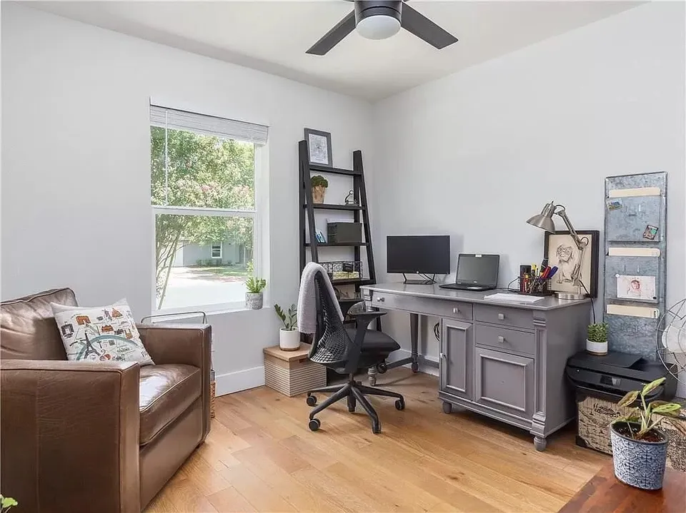 Home office with a leather chair, a grey desk and a ladder shelf