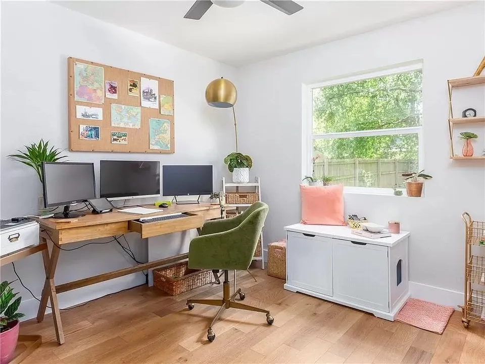Home office with two desks, a cork board and a window