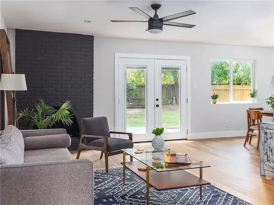 Living room with a black brick fireplace wall and French doors to the yard
