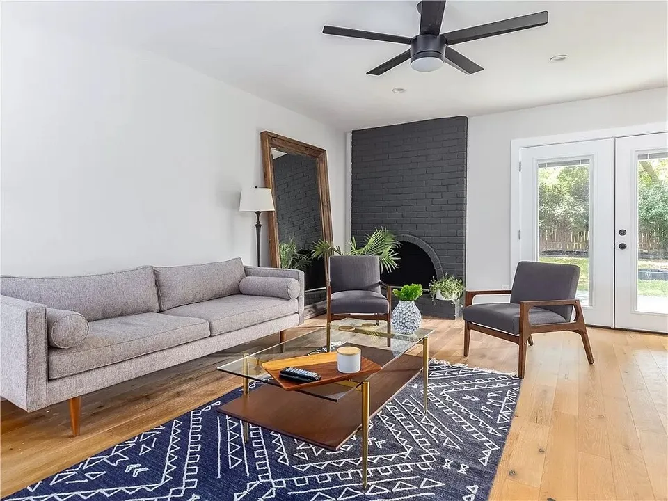 Living room with a painted black brick fireplace, a grey sofa and French doors