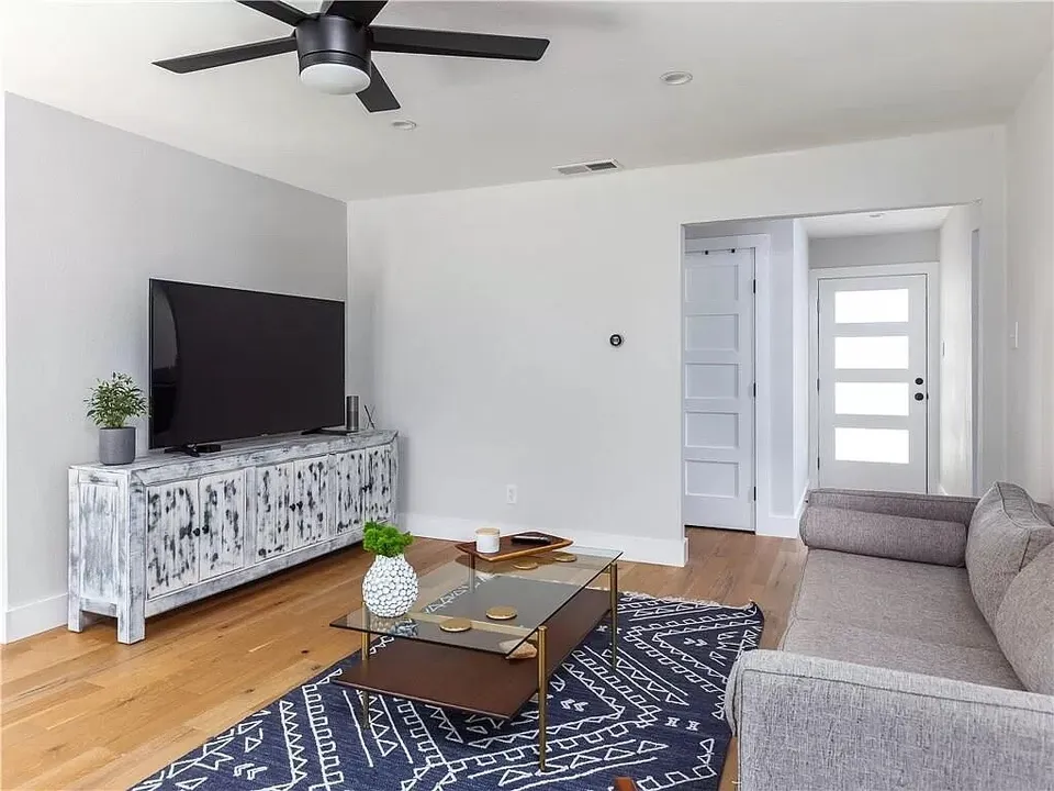 Living room with a TV console and a front door with glass panels