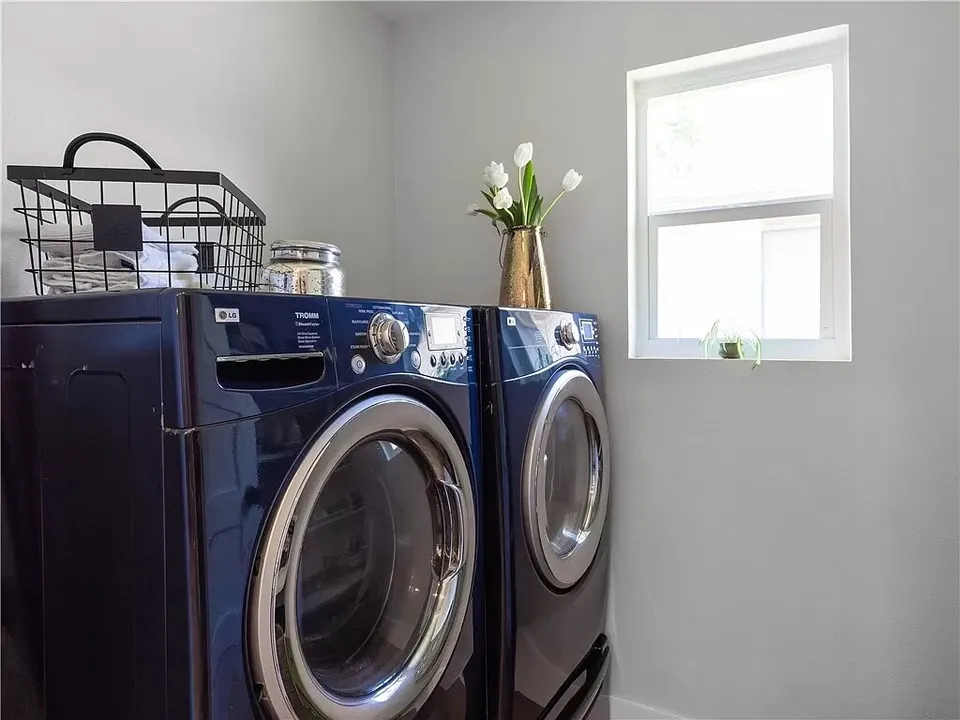 Navy front-load washer and dryer beside a window