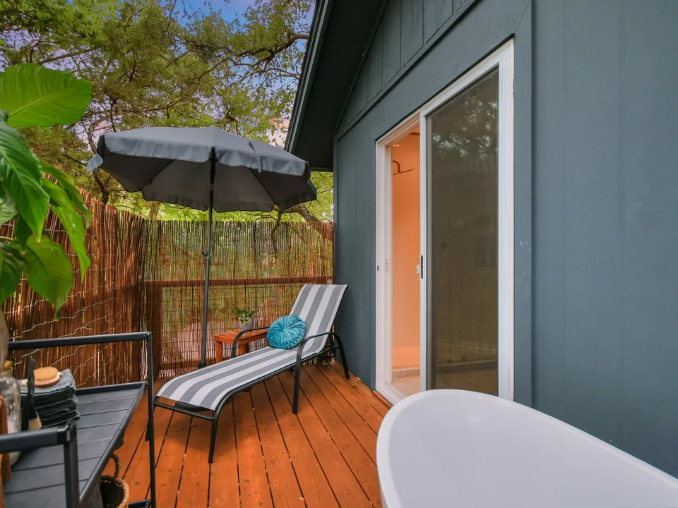 Balcony with an outdoor soaking tub, a lounge chair and reed privacy screens