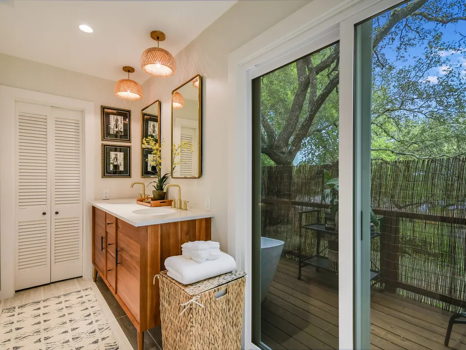 Bathroom with a wood vanity, brass pendants and sliding doors to the balcony