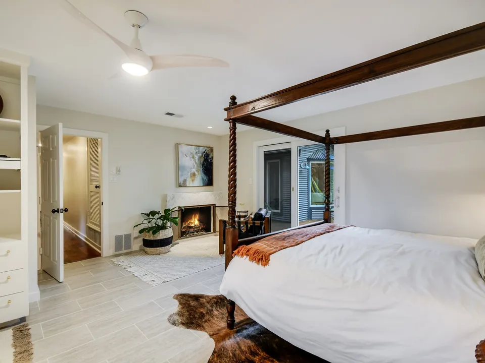 Bedroom with a four-poster bed, built-in shelves and a corner fireplace