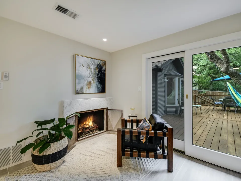 Corner fireplace with a marble surround beside sliding doors to the deck