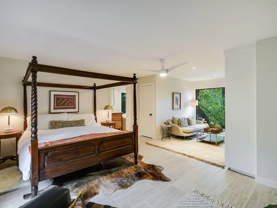 Primary bedroom with a four-poster bed, a cowhide rug and a sitting area