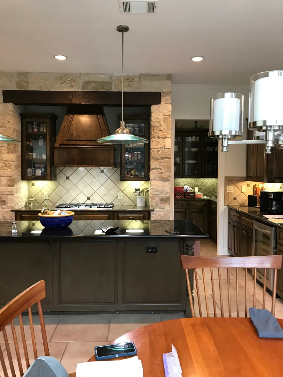 Kitchen before the remodel, with dark cabinets, a copper hood and a stone arch