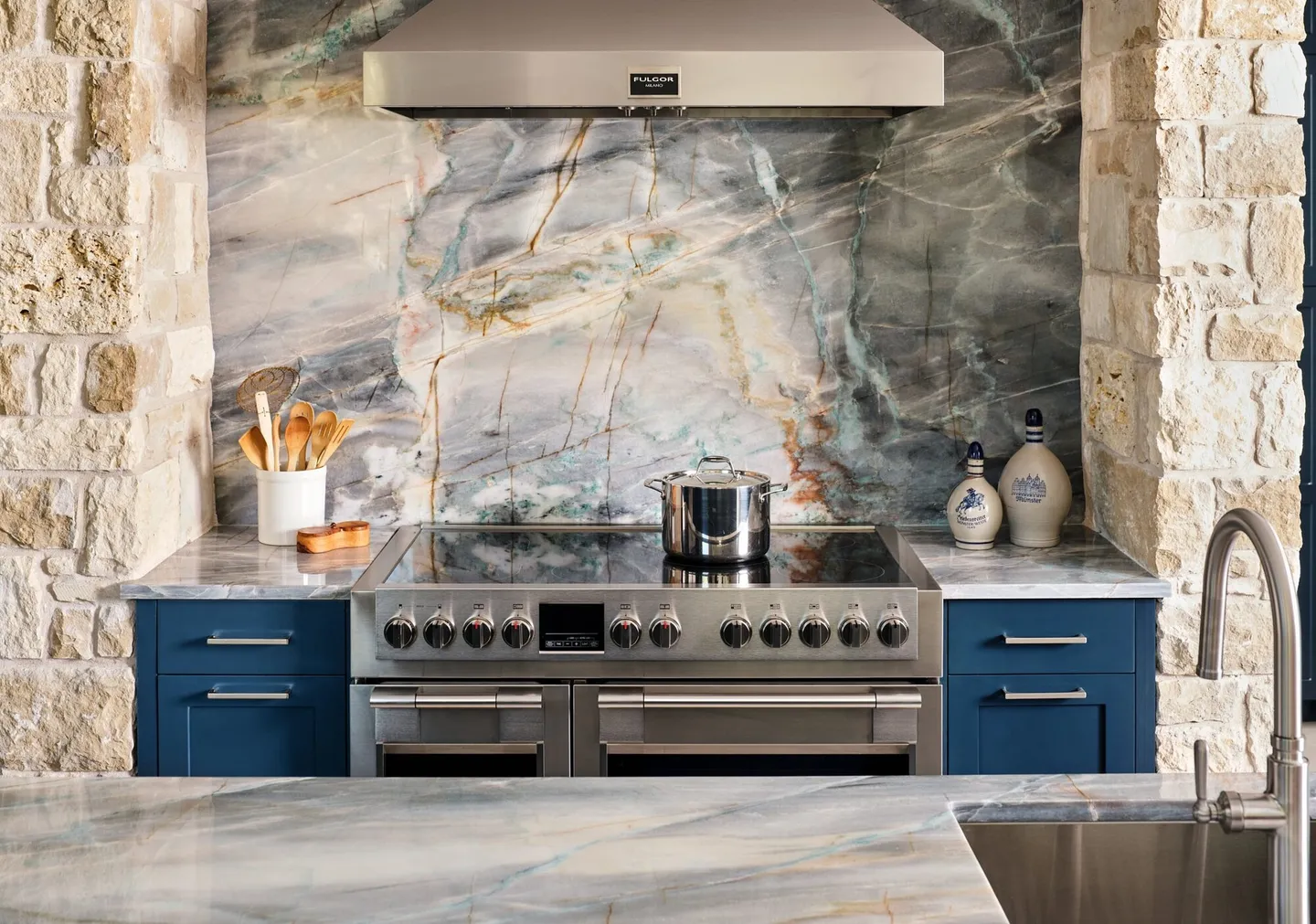 Range with a stainless hood in a limestone surround with a quartzite slab backsplash
