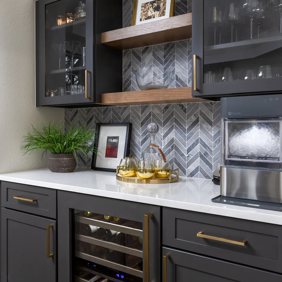Wet bar with charcoal cabinets, walnut floating shelves and grey chevron tile