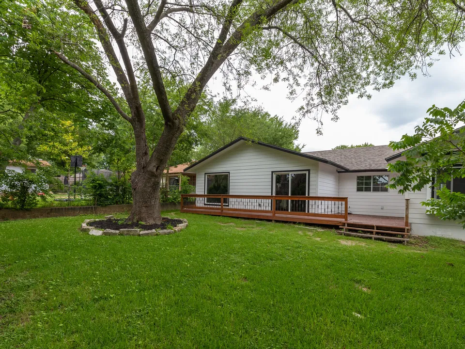 Backyard lawn with a large tree and the deck on the back of the house