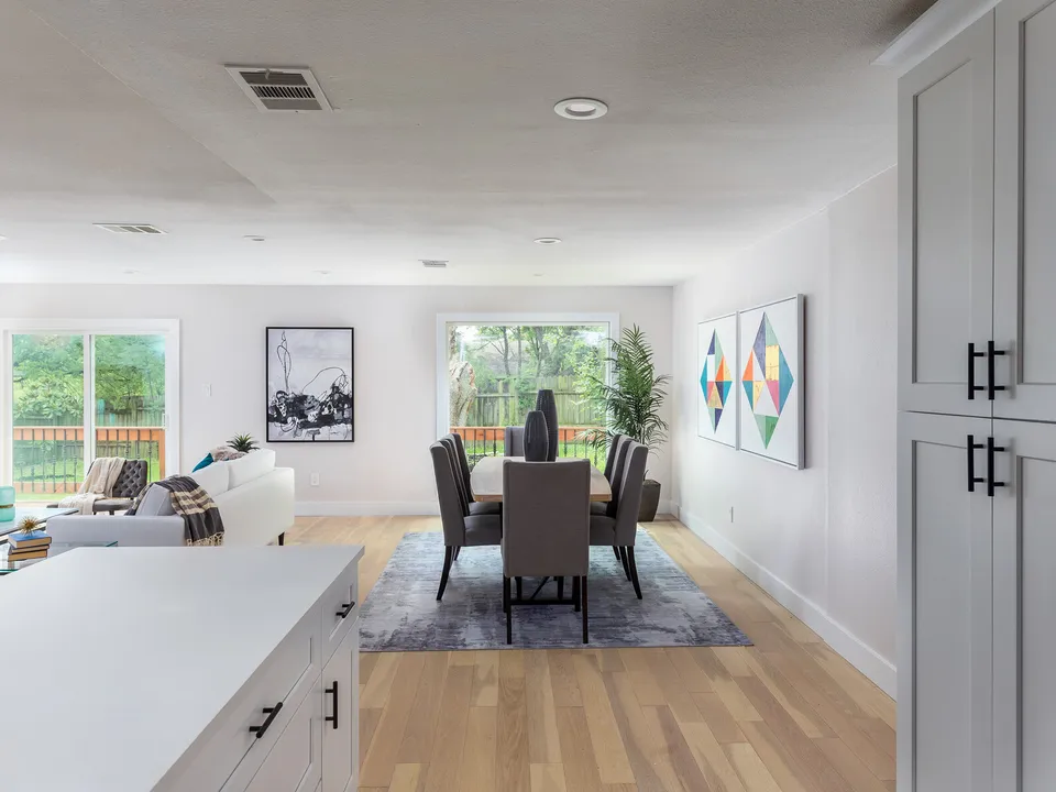 Dining area with a long table, seen past a white kitchen counter