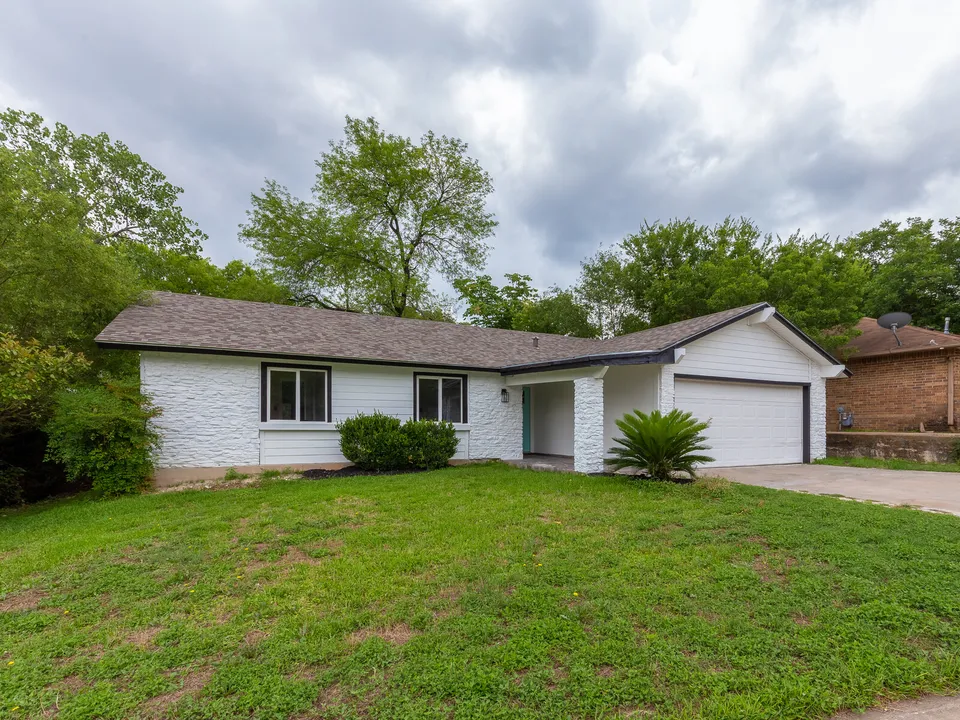 Front of the white painted brick ranch house and lawn