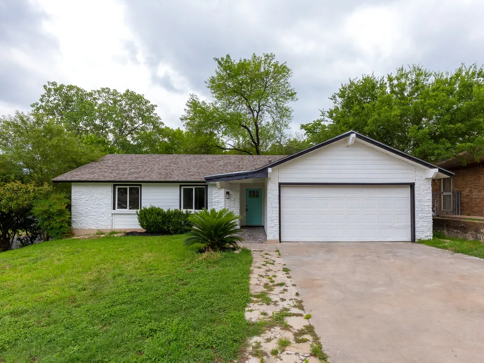 Ranch house with white painted brick, a garage and a teal front door