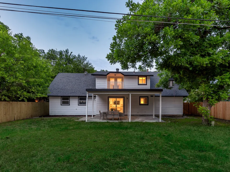 Back of the house with a new dormer and a covered patio at dusk
