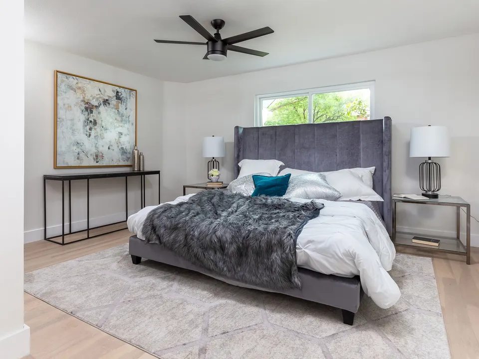 Bedroom with a grey channel-tufted bed and a large abstract painting