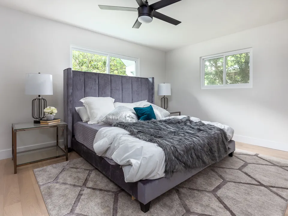 Bedroom with a grey tufted bed below two windows