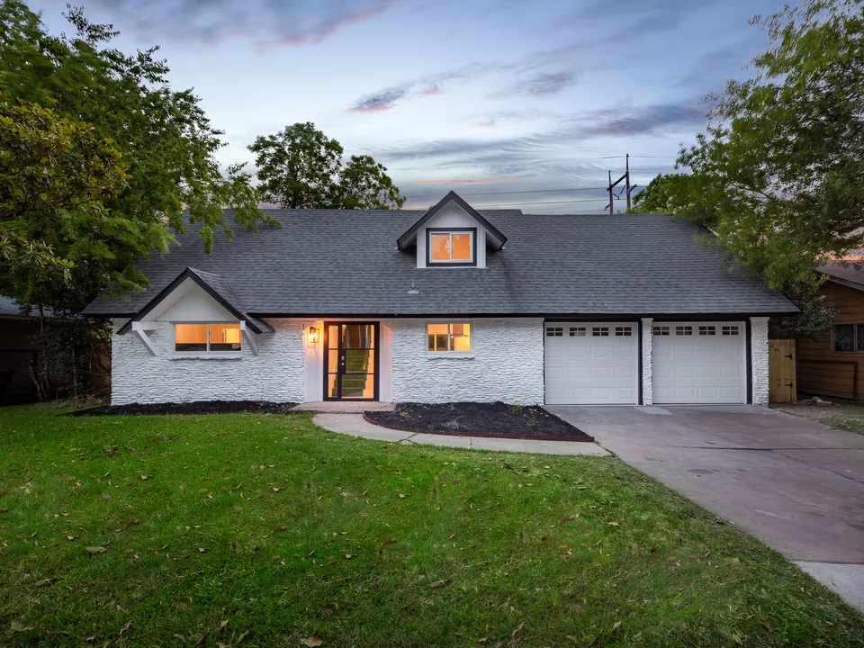 Front of the remodeled house with stone and a new gable at dusk