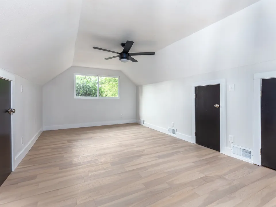 Long upstairs room with sloped ceilings and black doors